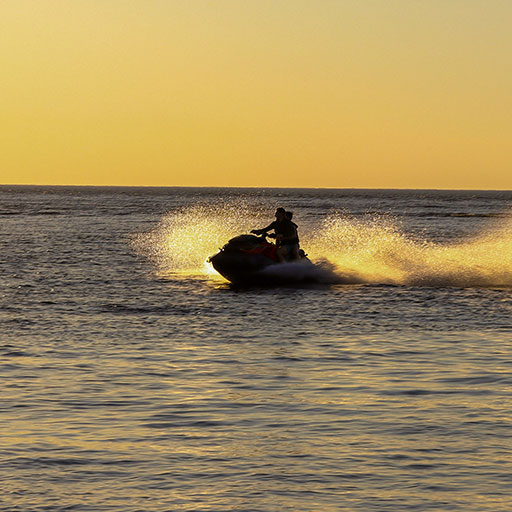 person riding a personal watercraft at sunset